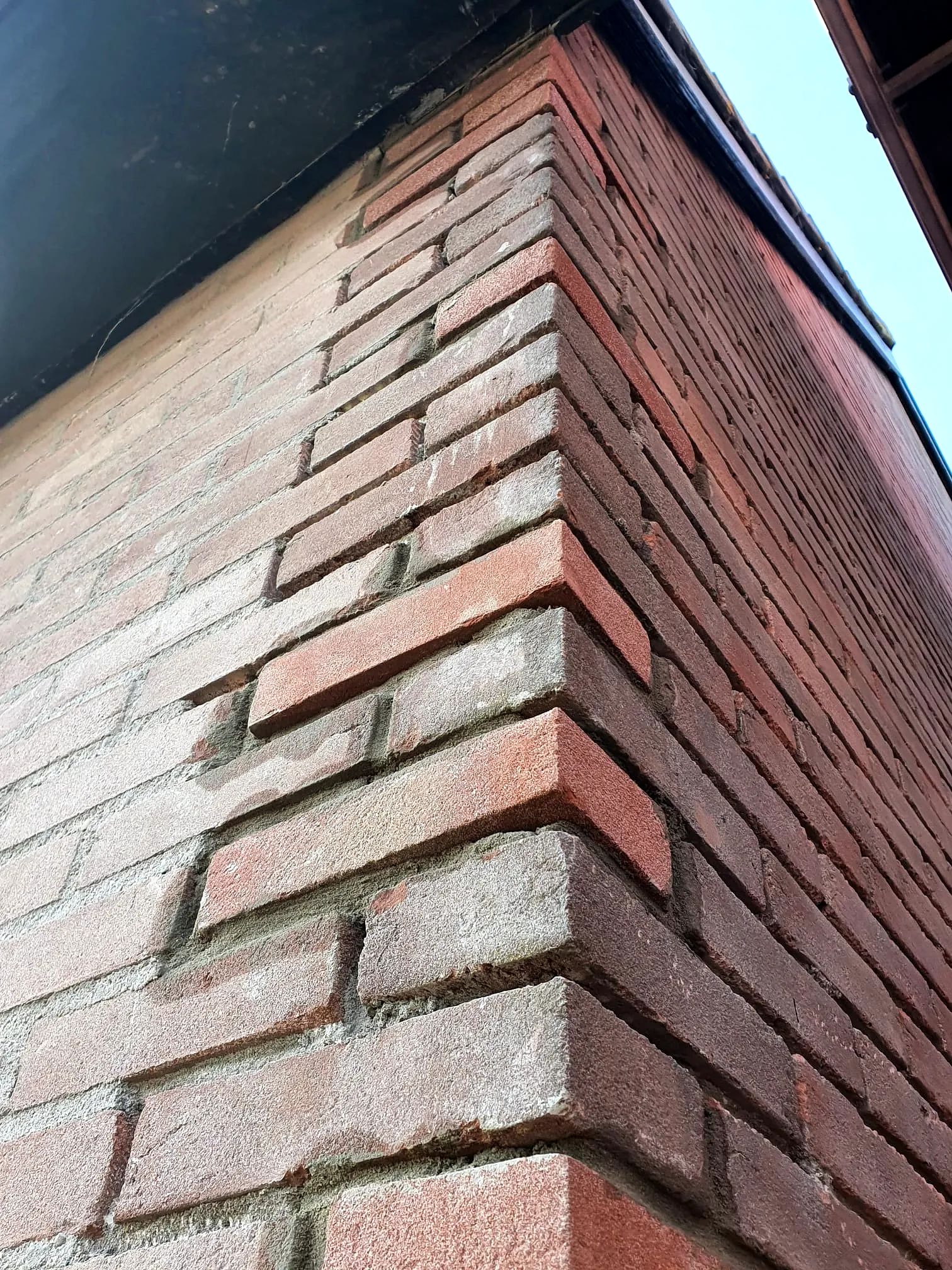 Herstelde gevelhoek met nieuw ingemetselde bakstenen en netjes afgewerkt voegwerk.